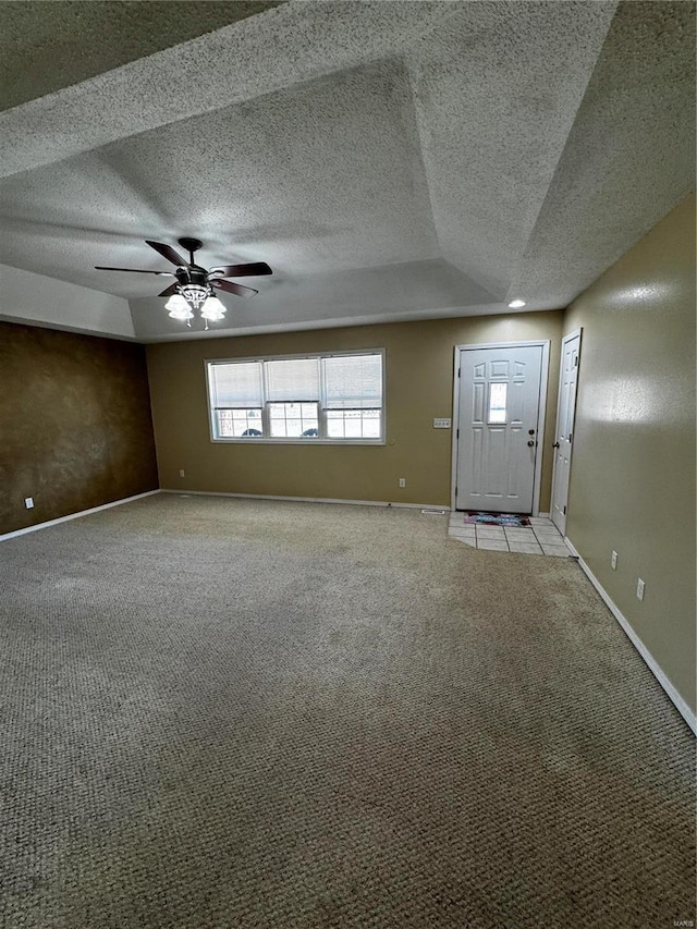 interior space with a ceiling fan, light colored carpet, baseboards, and a textured ceiling