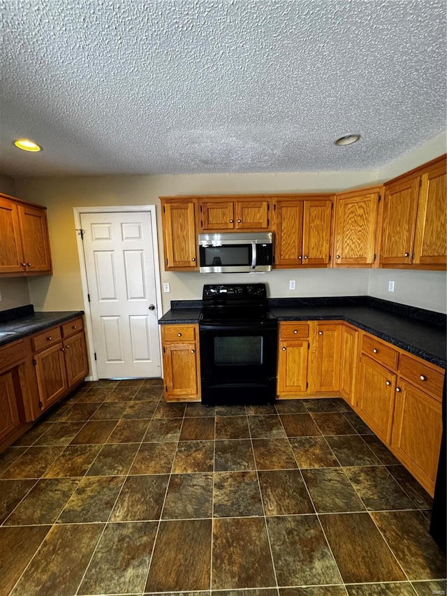 kitchen with brown cabinetry, stainless steel microwave, dark countertops, and black range with electric cooktop