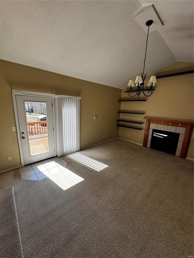 unfurnished living room featuring a tiled fireplace, lofted ceiling, a notable chandelier, and carpet flooring