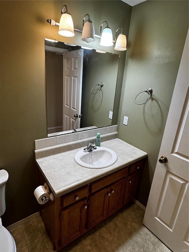 half bathroom with baseboards, toilet, and vanity