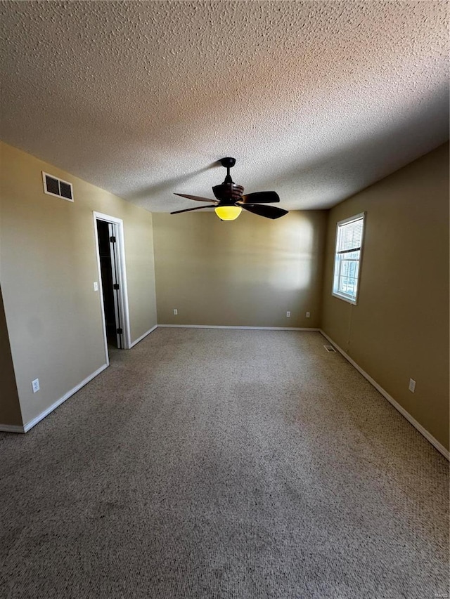 carpeted empty room featuring a textured ceiling, baseboards, visible vents, and ceiling fan