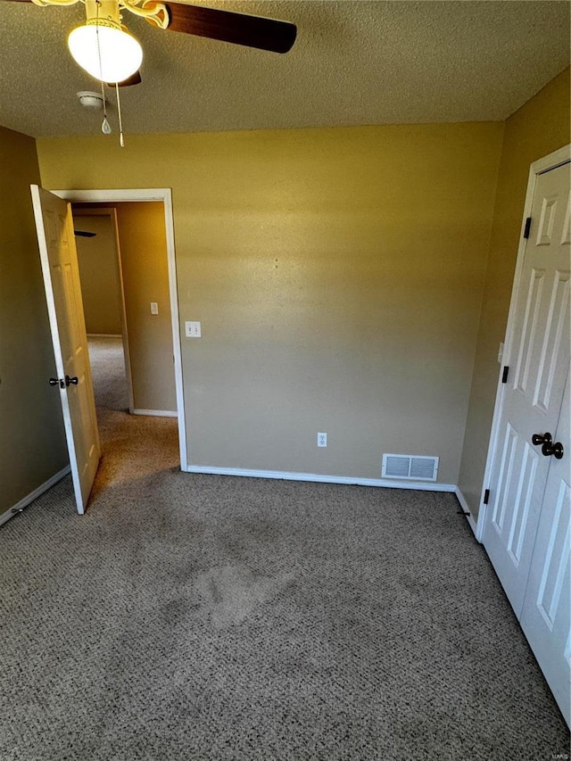 unfurnished bedroom featuring visible vents, baseboards, a textured ceiling, and carpet flooring