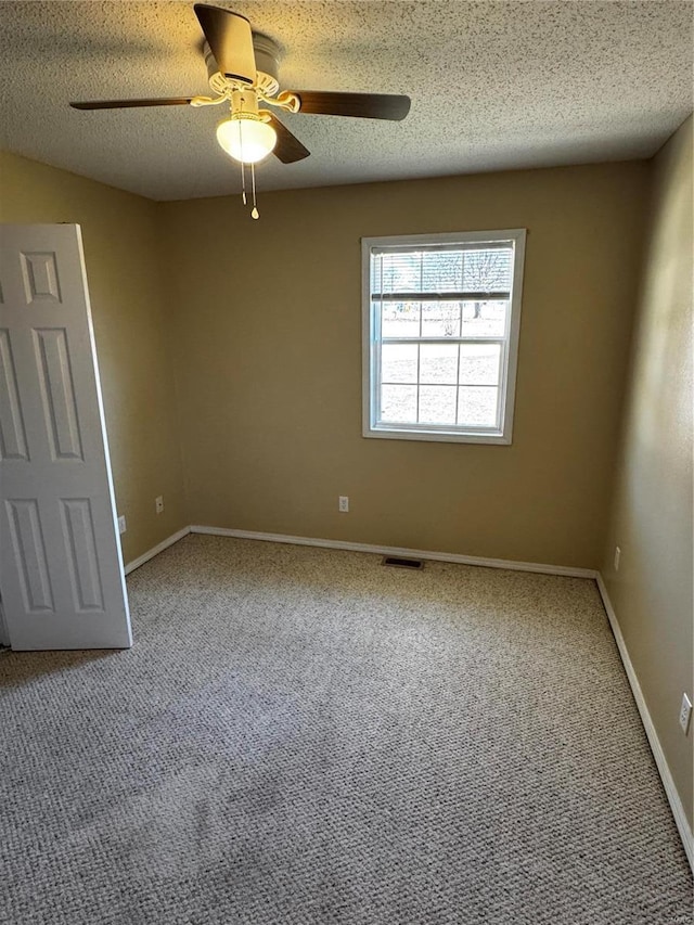 carpeted spare room featuring visible vents, baseboards, a textured ceiling, and a ceiling fan