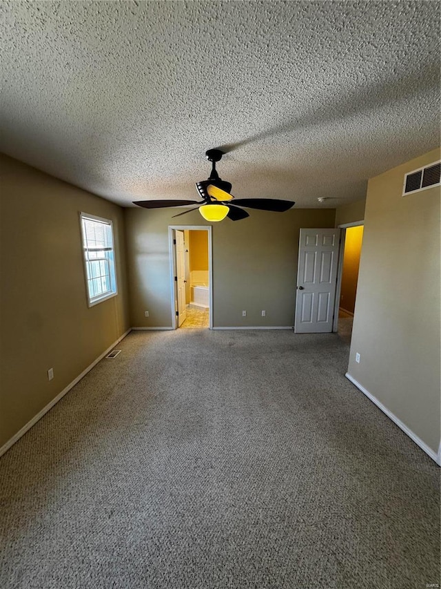 unfurnished room featuring visible vents, carpet flooring, a textured ceiling, and baseboards