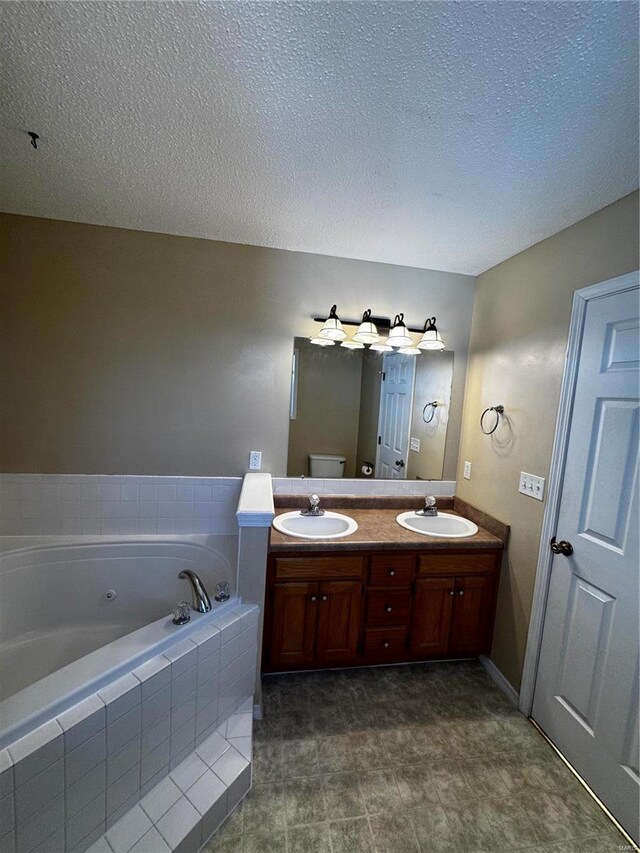 bathroom with a textured ceiling, double vanity, a bath, and a sink