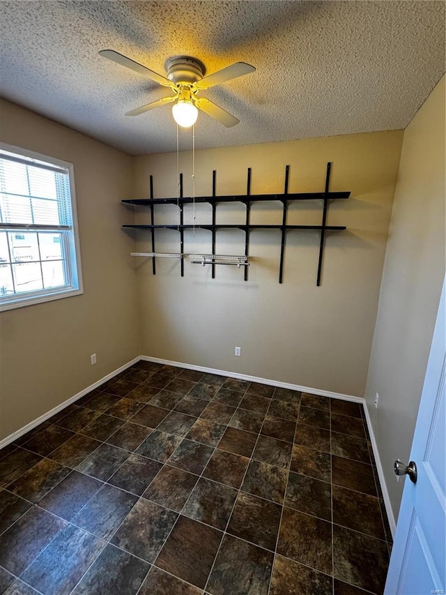 empty room featuring ceiling fan, a textured ceiling, and baseboards