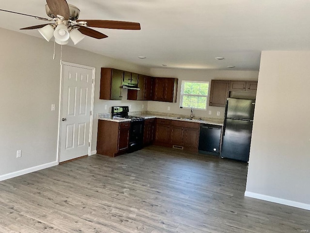 kitchen featuring light wood-style flooring, black appliances, light countertops, and a sink