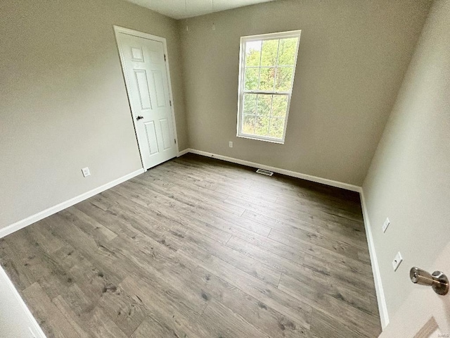 empty room featuring visible vents, baseboards, and wood finished floors