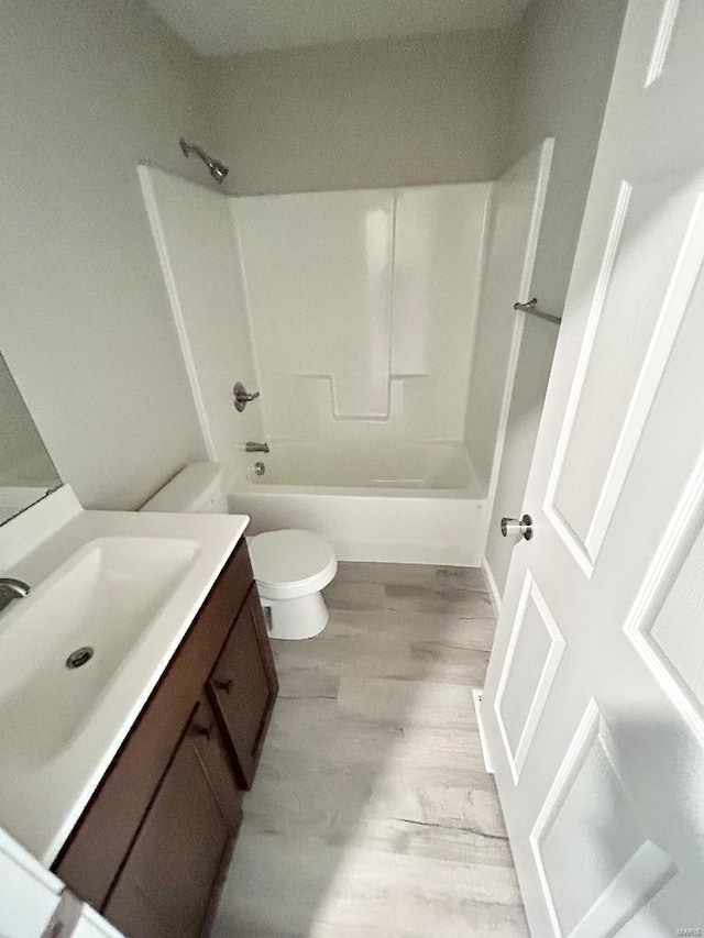 full bath featuring shower / bathtub combination, toilet, wood finished floors, and vanity