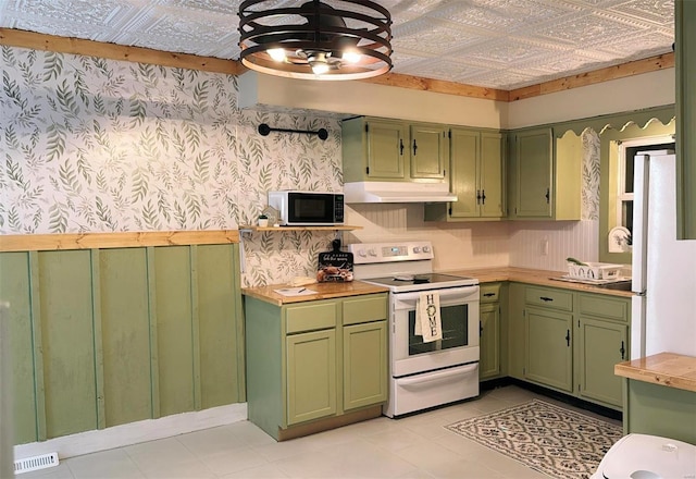 kitchen with under cabinet range hood, an ornate ceiling, green cabinets, and white appliances