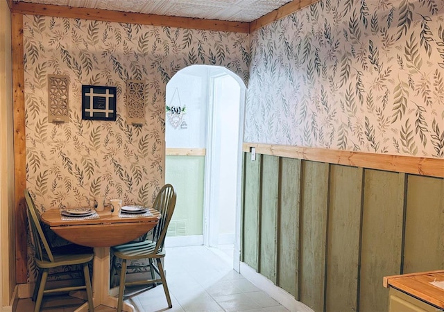 dining room featuring arched walkways and wallpapered walls