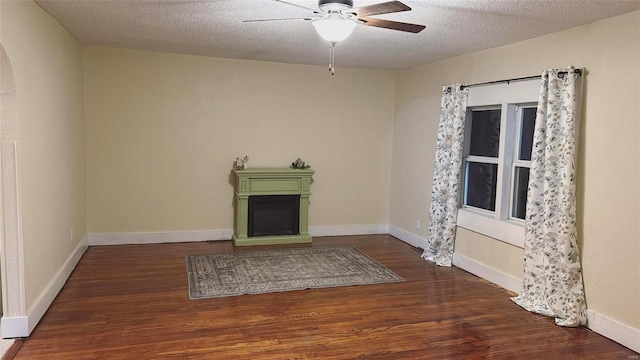 unfurnished living room with baseboards, a textured ceiling, wood finished floors, and a fireplace