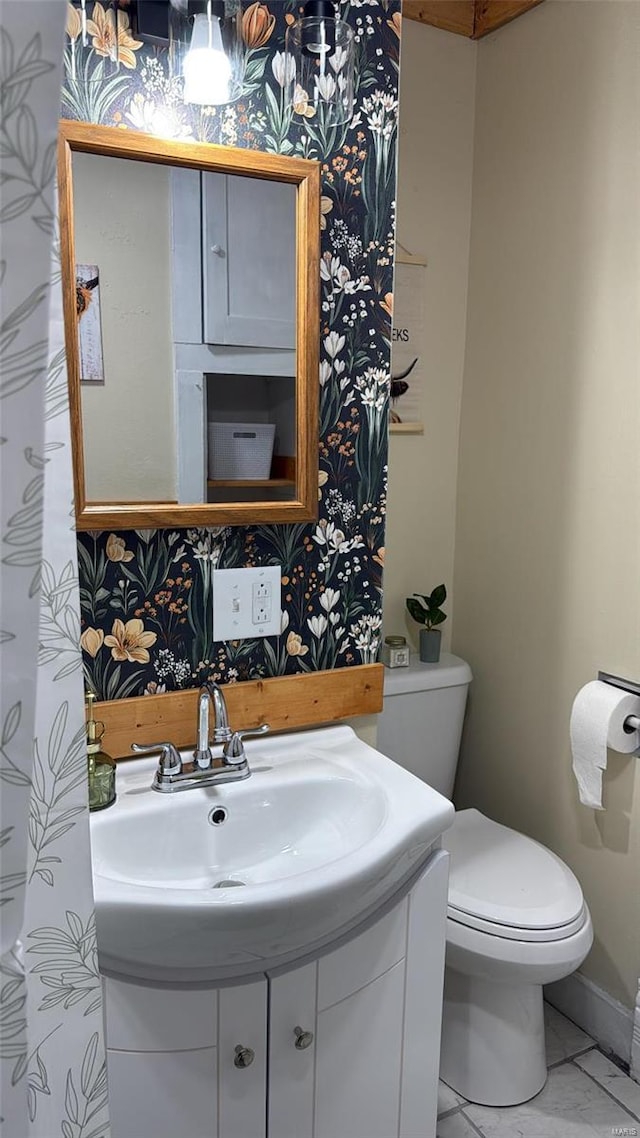 bathroom with toilet, vanity, marble finish floor, and baseboards