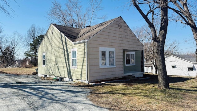 view of side of home featuring a yard, driveway, and a shingled roof