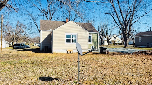 view of side of property featuring a lawn, a chimney, and a shingled roof