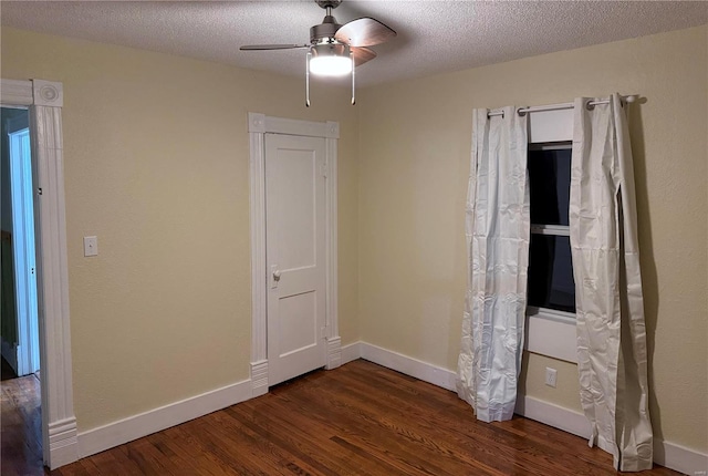 unfurnished bedroom with baseboards, a textured ceiling, and dark wood-style floors