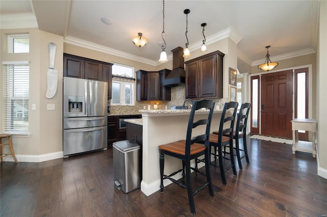 kitchen with dark brown cabinetry, plenty of natural light, stainless steel refrigerator with ice dispenser, and premium range hood