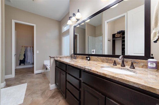 full bathroom featuring a walk in closet, a shower stall, baseboards, and a sink