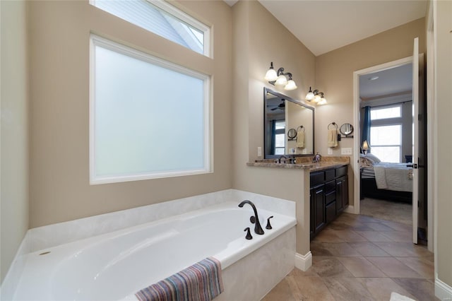 bathroom featuring a bath, vanity, ensuite bathroom, and baseboards