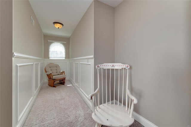 living area with a wainscoted wall, visible vents, carpet flooring, and a decorative wall