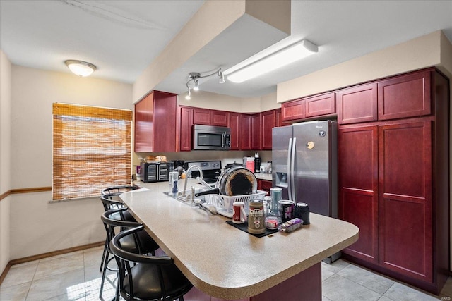 kitchen featuring light tile patterned floors, dark brown cabinets, stainless steel appliances, and light countertops