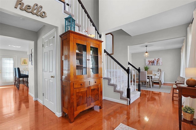 stairway with wood finished floors, baseboards, and a towering ceiling