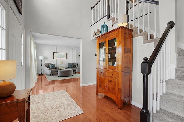 entrance foyer featuring baseboards, a high ceiling, wood finished floors, and stairs