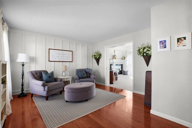 sitting room with baseboards, wood finished floors, and a fireplace