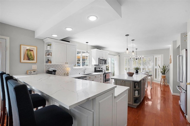 kitchen featuring open shelves, a sink, white cabinetry, appliances with stainless steel finishes, and a peninsula