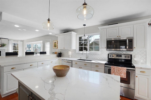 kitchen with a peninsula, a sink, stainless steel appliances, white cabinetry, and backsplash