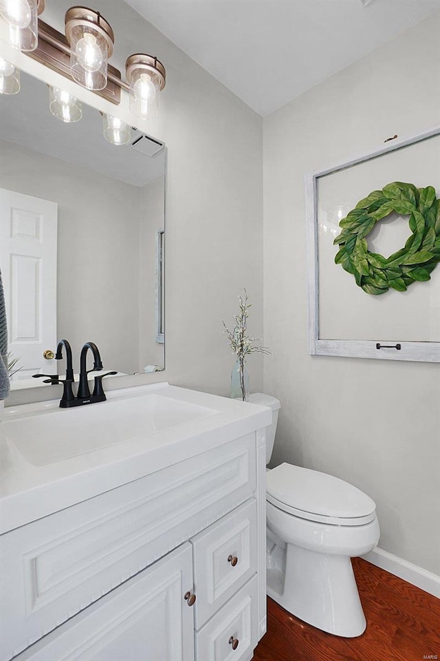 bathroom featuring visible vents, toilet, wood finished floors, baseboards, and vanity