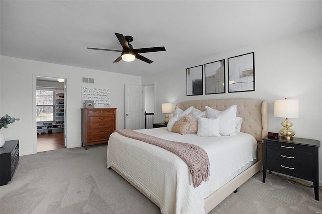 bedroom with light carpet, visible vents, and a ceiling fan