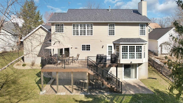 rear view of house featuring a lawn, a patio, a chimney, and a deck