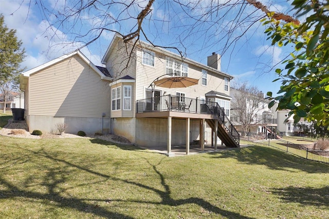 back of property featuring stairway, fence, a chimney, a deck, and a lawn