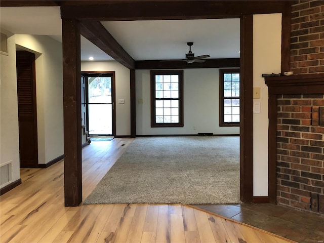 unfurnished room with beam ceiling, baseboards, light wood finished floors, and ceiling fan