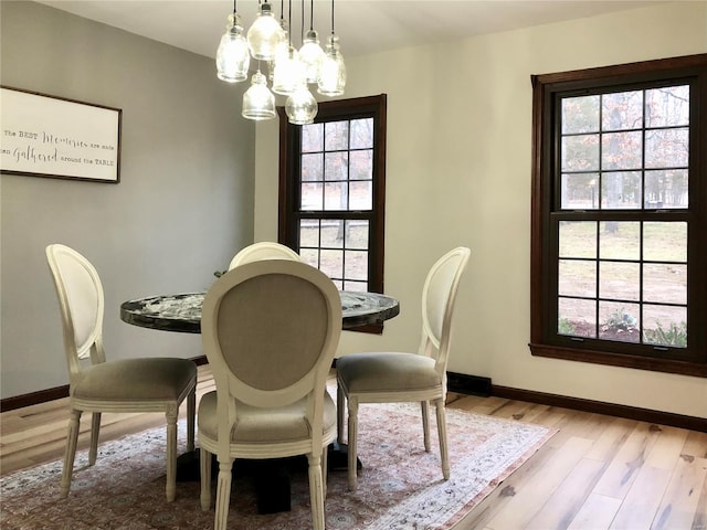 dining area with baseboards, a healthy amount of sunlight, light wood-style flooring, and an inviting chandelier