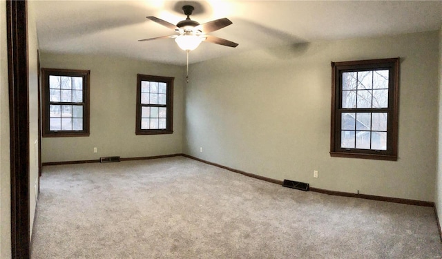 unfurnished room featuring a ceiling fan, carpet, visible vents, and baseboards