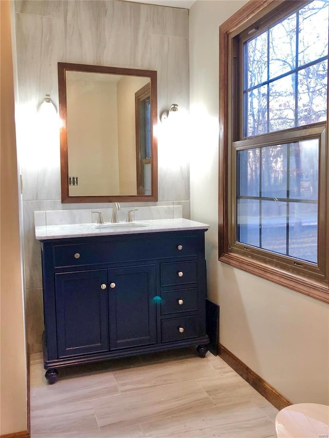 bathroom with vanity, toilet, wood finished floors, and baseboards