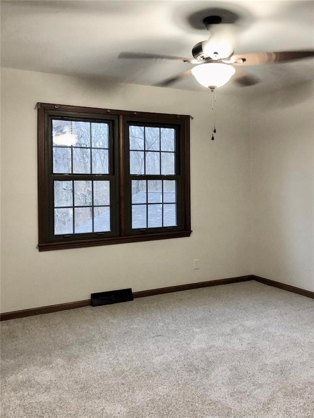 carpeted spare room featuring baseboards, plenty of natural light, and a ceiling fan