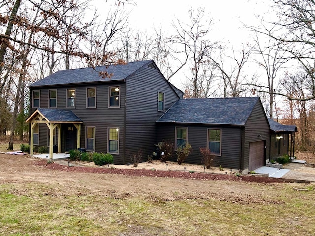 view of front of property featuring a garage, covered porch, driveway, and a shingled roof