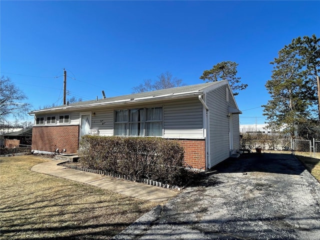 exterior space featuring brick siding, a lawn, and fence