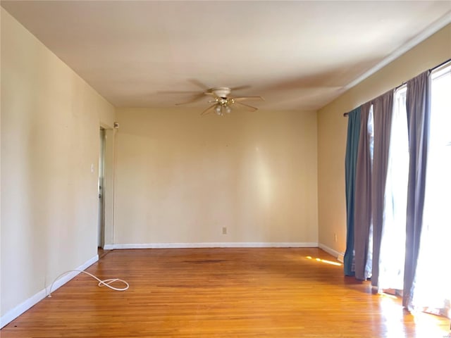 spare room featuring light wood-type flooring, baseboards, and ceiling fan