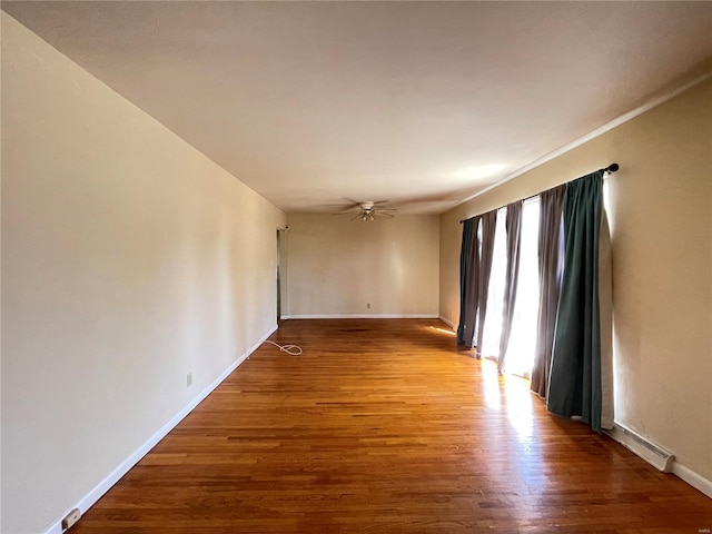 empty room with a ceiling fan, wood finished floors, and baseboards