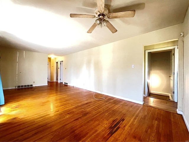 empty room featuring visible vents, baseboards, a ceiling fan, and hardwood / wood-style flooring