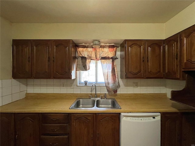 kitchen with light countertops, white dishwasher, backsplash, and a sink