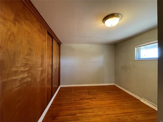 empty room featuring baseboards and dark wood finished floors