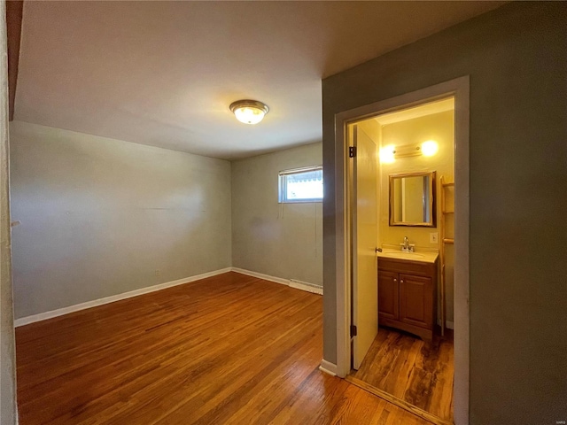 unfurnished bedroom with a sink, connected bathroom, baseboards, and dark wood-type flooring