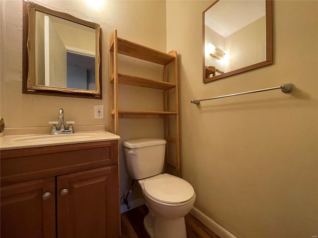 half bathroom with toilet, vanity, and baseboards