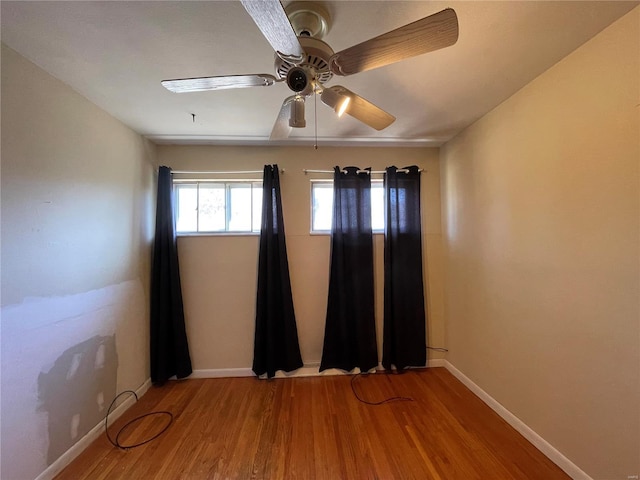 spare room featuring baseboards, wood finished floors, and a ceiling fan