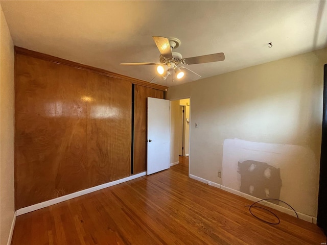 unfurnished bedroom with a closet, ceiling fan, baseboards, and wood finished floors